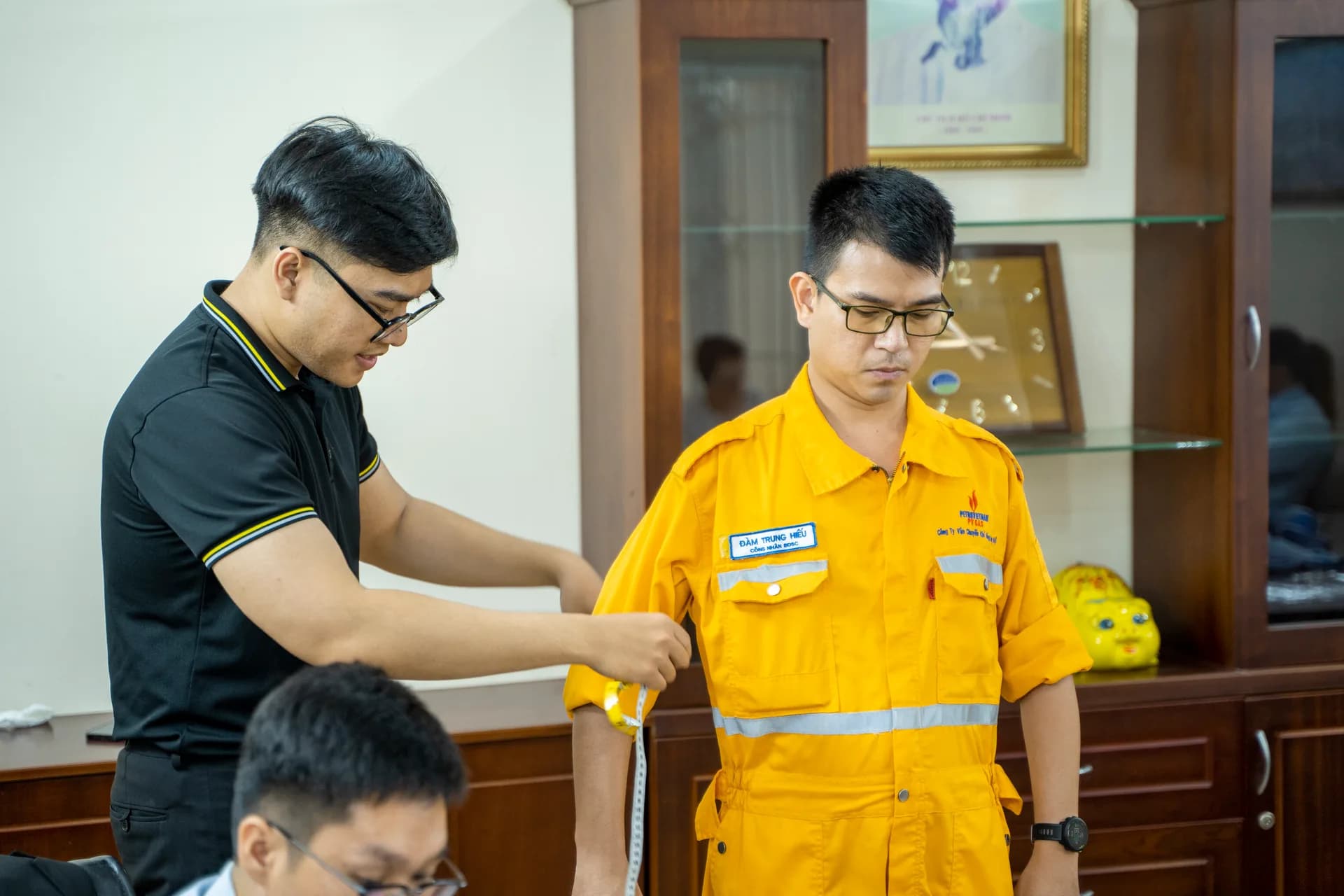 Đo bắp tay cho công nhân đang mặc áo bảo hộ PV GAS — mặc vest nên mặc rộng hay vừa