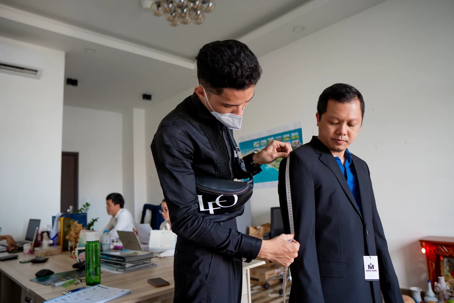 Đo bắp tay áo vest cho nhân viên, thẻ Mon Amie trên áo, minh họa bài cách xử lý vest nhăn, xỉn và ám mùi