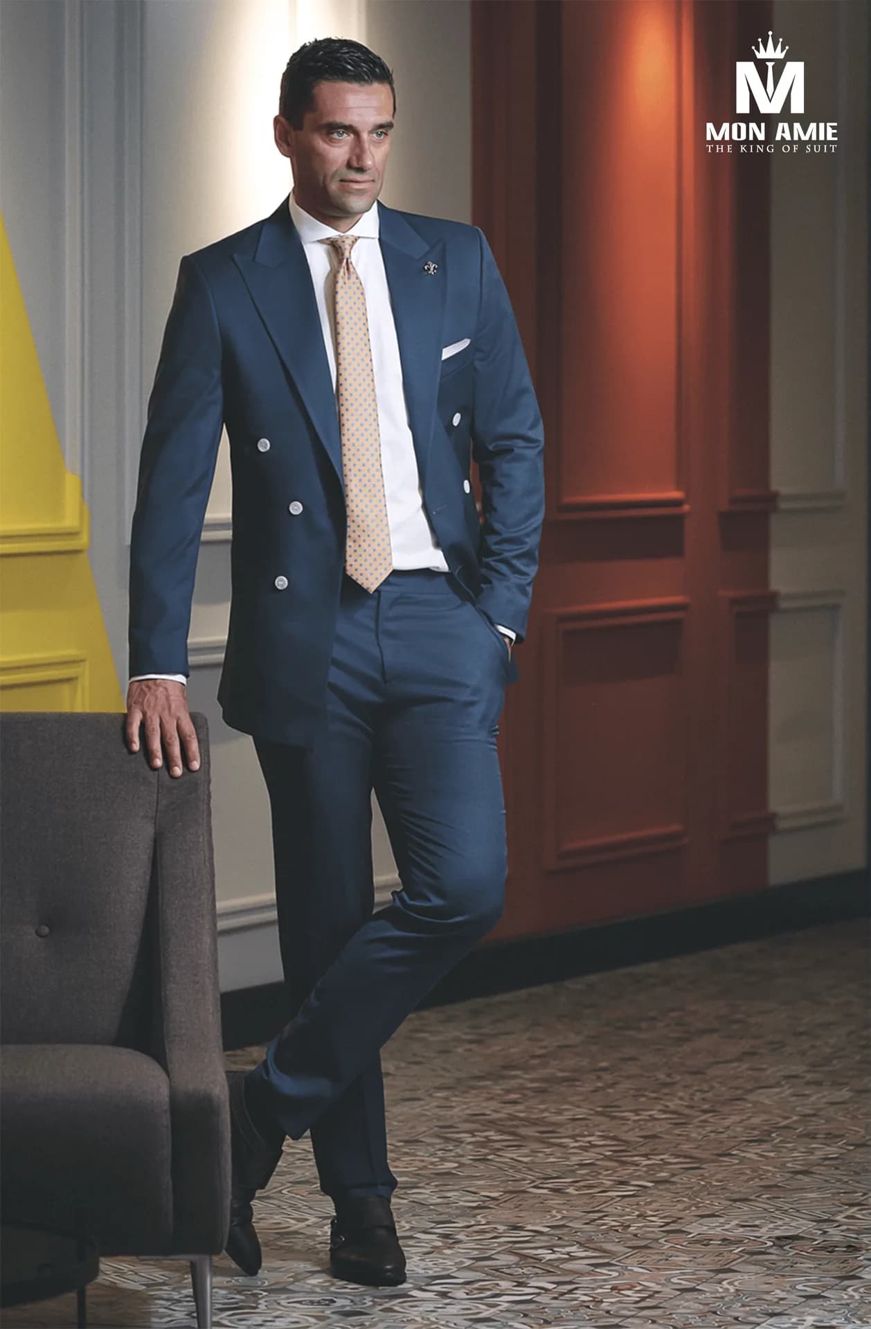 Suit xanh hai hàng khuy, cà vạt vàng nhạt, dáng đứng trong sảnh nhiều màu, một gam màu vest trẻ trung cho nam