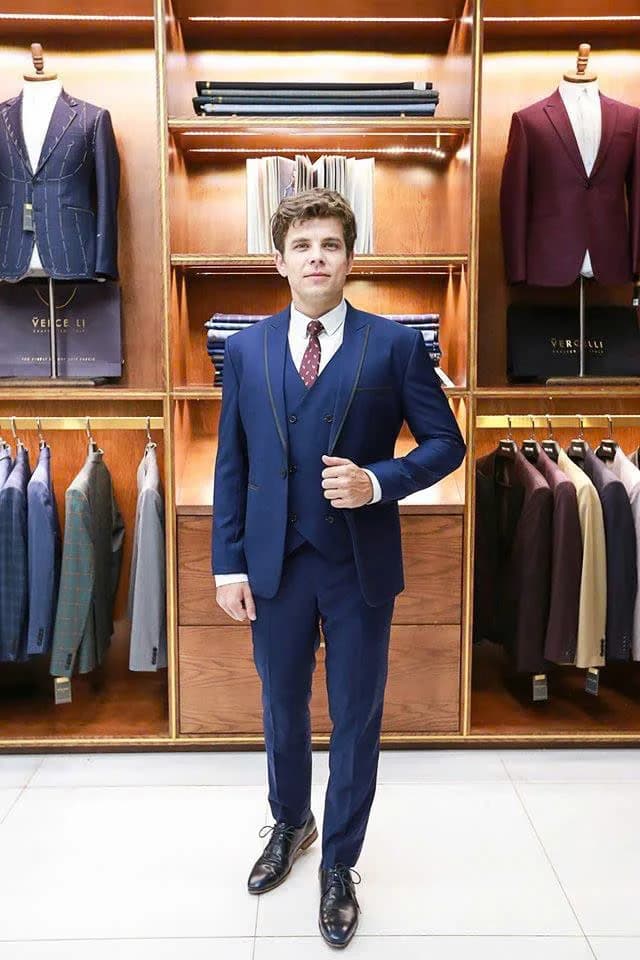 Chàng trai mặc vest xanh navy ba mảnh, cà vạt đỏ chấm bi, minh họa cách người gầy mặc vest đầy đặn hơn