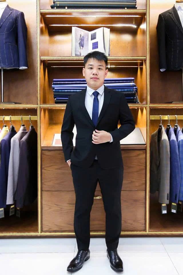 Chàng trai vest đen, cà vạt xanh navy trong showroom gỗ của Mon Amie, hình ảnh không gian tư vấn tại showroom Hồ Văn Huê