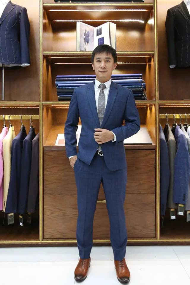 Quý ông trung niên mặc vest xám caro navy, cà vạt xám và giày nâu, minh họa cách phối giày với vest xám