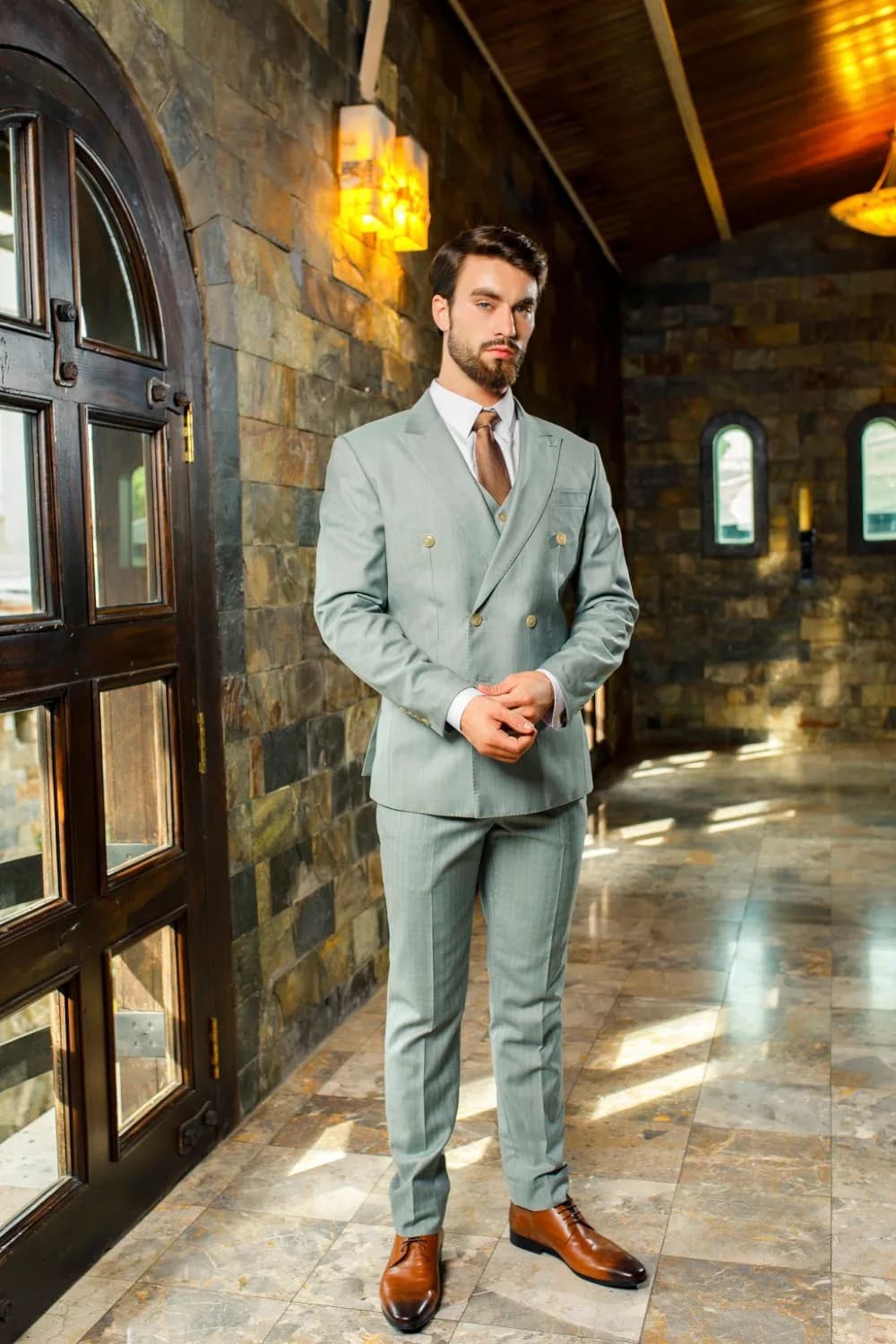 Bộ suit ba mảnh xanh sage cài hai hàng, giày da nâu, minh họa tiệm may vest ở Phú Nhuận