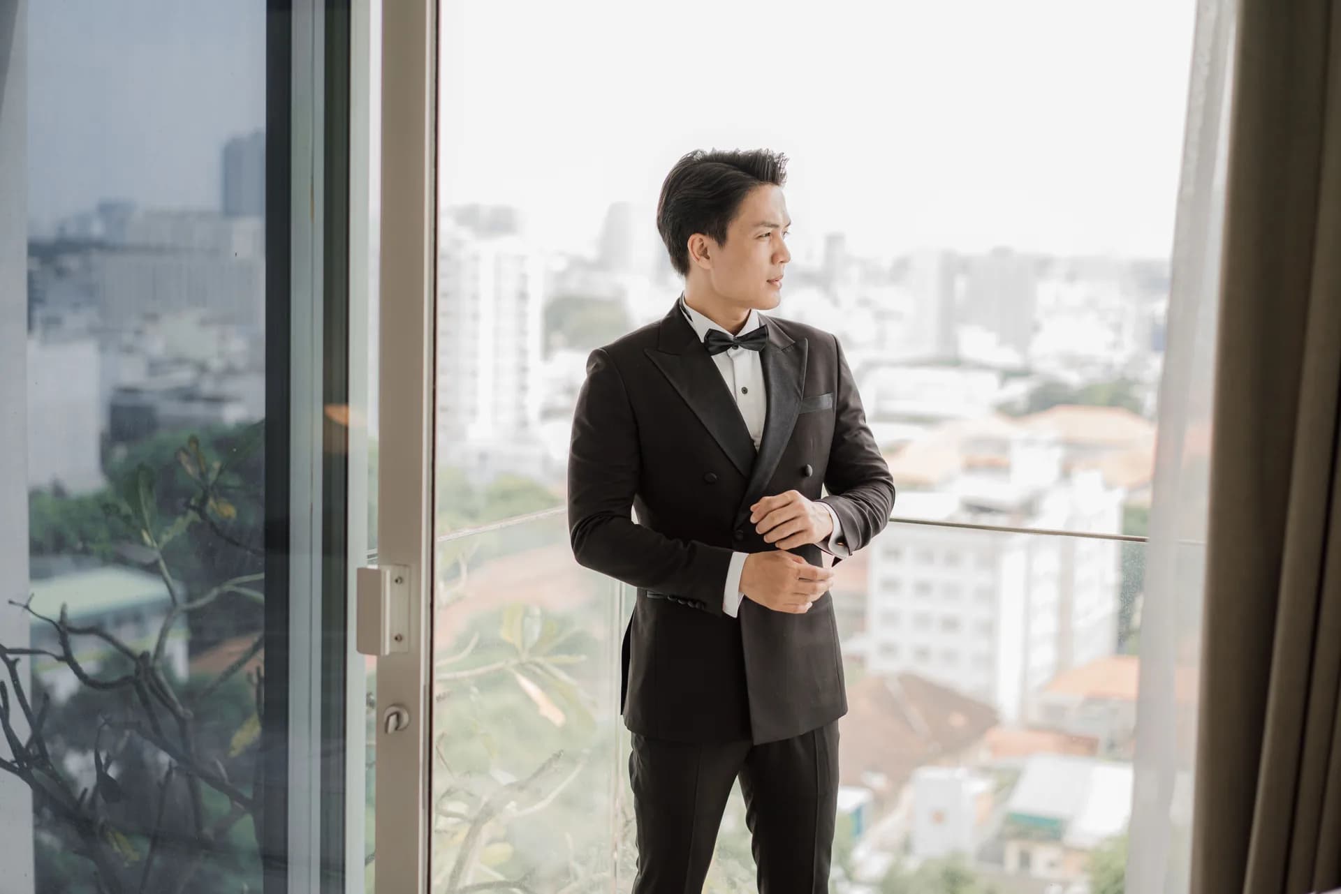 Chỉnh măng sét bên ban công nhìn ra thành phố, minh họa tiệm may vest Bình Thạnh và Thủ Đức